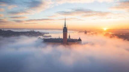 Fototapeta premium A serene sunrise over a fog-covered cityscape, highlighting a prominent tower.