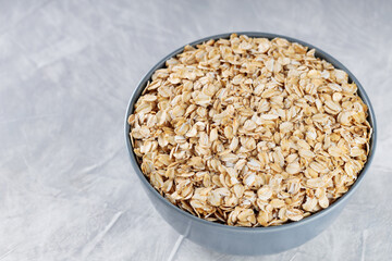 Bowl of Raw Rolled Oats on Textured Gray Background, Healthy and Nutritious Breakfast Ingredient, Copy Space