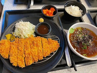 Crispy tonkatsu, a Japanese-style breaded and deep-fried pork cutlet, served with shredded cabbage and drizzled with savory sauce. A delightful balance of crunchy texture and juicy meat.
