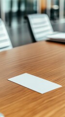 A blank white card lies on a wooden table in a conference room.