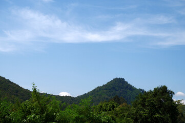 Mountain in countryside with bright blue sky background. Nature background of sky and mountain. Abundance, natural light, green, trees, sunny day, landscapes, beautiful, and travel in Asia concept.