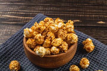 Snack concept, sweet caramelized popcorn in a bowl on a gray, wooden background