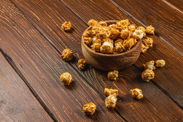 Snack concept, sweet caramelized popcorn in a bowl on a gray, wooden background