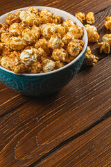 Snack concept, sweet caramelized popcorn in a bowl on a gray, wooden background
