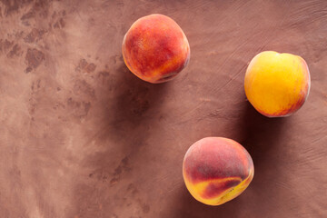 Fresh Ripe Peaches on Textured Brown Surface with Dramatic Shadows, Top View, Copy Space