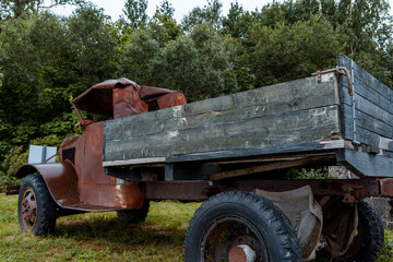 A rusty, vintage truck sits abandoned in a grassy field, showcasing its weathered metal and...