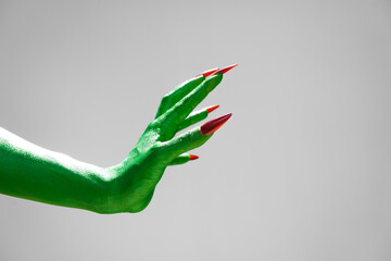 Green  female monster hand with sharp nails, isolated on a white background, exudes horror and...