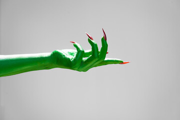 Green  female monster hand with sharp nails, isolated on a white background, exudes horror and...