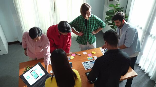 Top view of skilled Ui designer brainstorming by writing on sticky notes and planning about Ux Uo design or mobile phone interface wireframe design with diverse develop team at boardroom. Convocation.