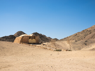 Native tribe of Egypt habitat home solitary structure in a barren desert landscape, surrounded by rocky hills under a clear blue sky