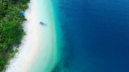 Aerial view of tropical beach with white sand, turquoise ocean and blue sky.