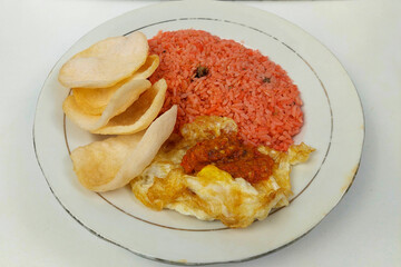 Red fried rice, fried egg and crackers on a white plate