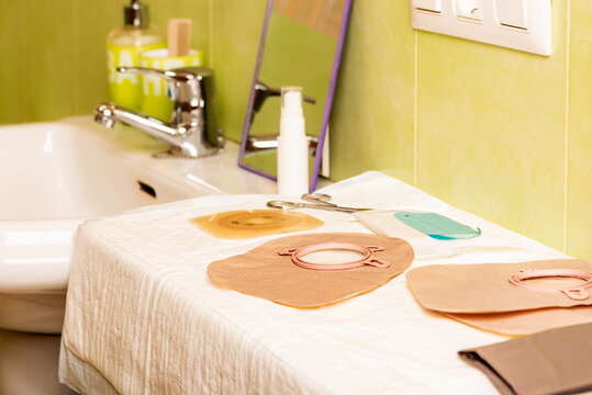 Preparing to change an adhesive barrier and ostomy bag in a bathroom, with a small mirror to ensure proper adhesive placement.