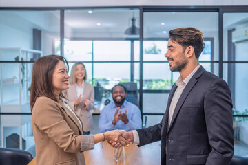 multiracial business partnership meeting in the office room, an asian businesswoman smile shaking hand with caucasian businessman for the future business cooperation