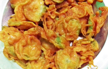 Golden-brown crispy snacks are piled on a plate, glistening with a slight sheen, suggesting they are freshly fried. The pieces appear uneven in shape, hinting at a homemade preparation.