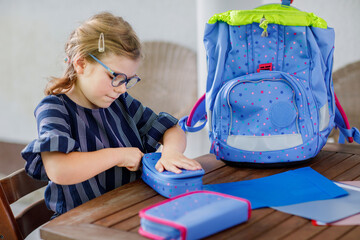 Happy smiling girl preparing for school her backpack. First day of school. Back to school concept....