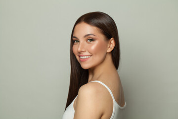 Smiling brunette woman with glowing skin, subtle makeup and a gentle smile. Young model posing,...