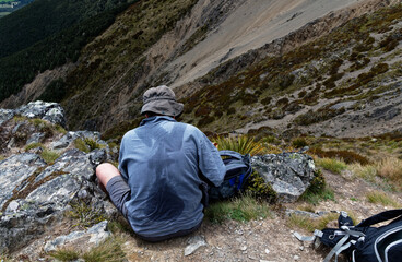 A man has been hiking or tramping and has a sweaty back
