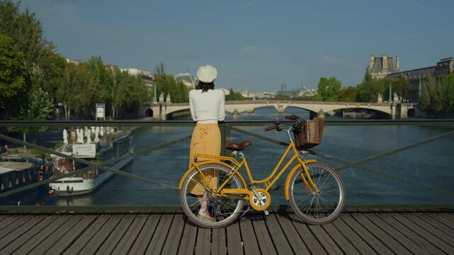 Woman with Yellow Bicycle on Bridge Overlooking River
