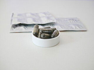 The herbal capsule is in the bottle cap and behind it is a blister pill packaging