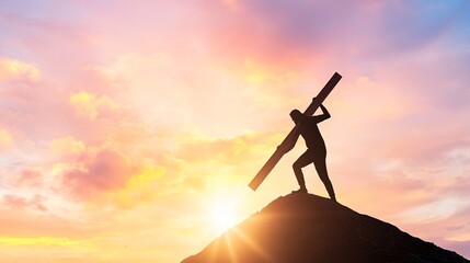 Crucifix faith religion wood concept. A person stands triumphantly on a mountain top, holding a large beam against a colorful sunset.