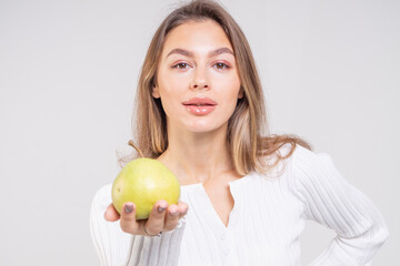 Close-up portrait of attractive brunette young woman holding a yellow pear on a white background. Copy space