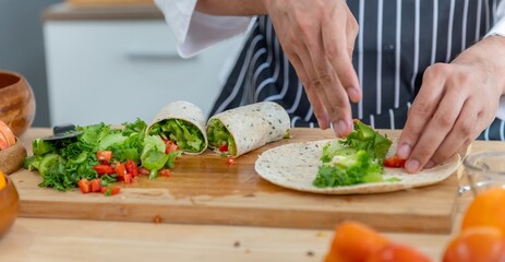Chef is preparing a wrap with lettuce and tomatoes