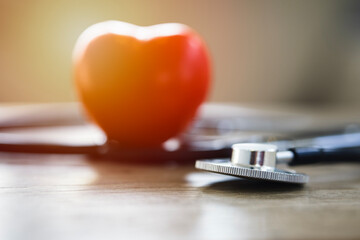 Heart and stethoscope on table with sunlight streaming in, concept of health insurance, family...