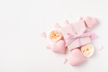 Greeting card for Valentine or Mothers Day. Pink hearts, rose flowers and gift box on table top view. Flat lay composition.