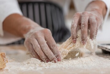 professional Chef sifting flour powder and sprinkling ingredients on massaging dough for bakery...