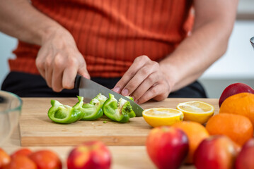 Hand chef knife cut and slice fresh Vegetables baby cos salad on wood board table .Make Salad Organic Vegetables mix lunch with green vegetables and fruit at kitchen table on wood cutting board.