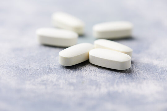 Arginine alpha-ketoglutarate (AAKG) tablets. Bodybuilding food supplements on wooden background. Soft focus. Close up. Copy space.