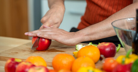 Hand chef knife cut and slice fresh Vegetables baby cos salad on wood board table .Make Salad Organic Vegetables mix lunch with green vegetables and fruit at kitchen table on wood cutting board.