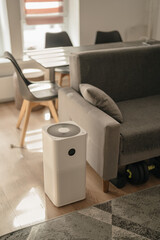 White air purifier from dust and viruses in the interior of the apartment with a dining table. Health and technology.