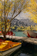 Fototapeta premium Upper Kachura Lake during autumn. Boats at jetty surrounded by yellow tree.