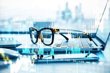 Financial market chart with glasses and laptop on desk, concept of analysis and growth.