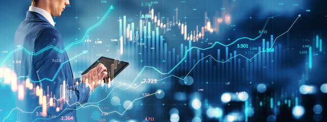 Businessman analyzing financial data on tablet with digital stock market graphs in futuristic background. Concept of trading and economy.