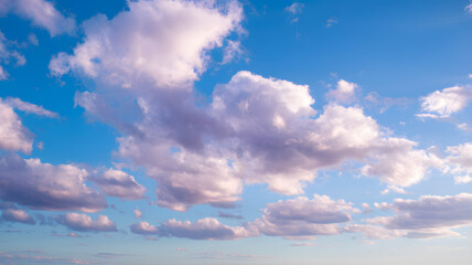 Obraz premium Cotton candy clouds in pastel hues float against a bright blue sky. A serene sky filled with fluffy white clouds against a bright blue background, creating a peaceful and calming atmosphere.