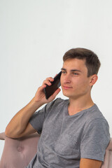 Confident young man talking with mobile phone while sitting in chair on white background