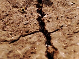 Close-up of cracked dried up soil . The texture of the dry and dehydrated soil with cracks close-up. The ground cracks, hot climate, lack of moisture.