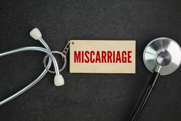 stethoscope and wooden tag with the word miscarriage. the concept of miscarriage. termination of...