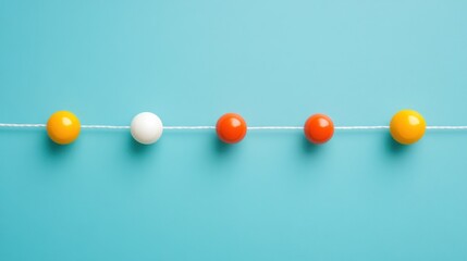 Obraz premium Colorful balls strung on a thread against a light blue background.