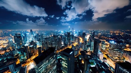 Fototapeta premium Stunning Aerial Night View of a Modern Cityscape with Illuminated Skyscrapers and Vibrant Urban Lights Under a Dramatic Cloudy Sky