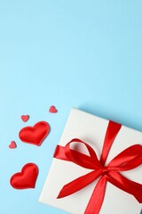Gift box with red hearts on color background