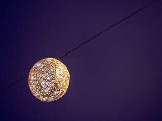Illuminated Christmas ball decoration against dark blue night sky. Festive season celebrations.