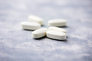 Arginine alpha-ketoglutarate (AAKG) tablets. Bodybuilding food supplements on wooden background. Soft focus. Close up. Copy space.