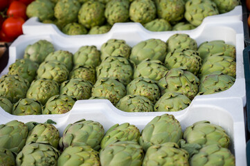 Obraz premium a bunch of green artichoke are stacked on white plastic containers.