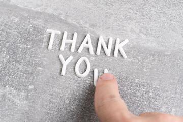 White letters forming word thank you on gray concrete background.