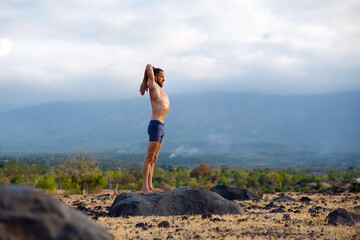 Man Practicing Yoga Meditation Outdoors in Nature with Mountain View.