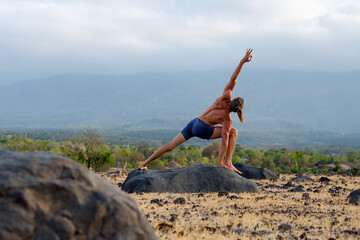 Man Practicing Yoga Meditation Outdoors in Nature with Mountain View.